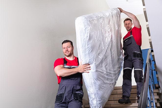 team carrying a large box spring out of a bedroom in Chepachet